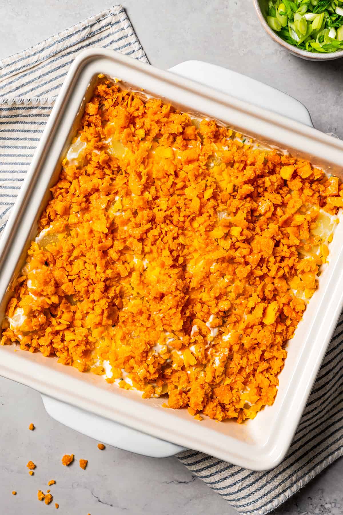 Cheesy potatoes in a baking dish topped with cracker crumbs.