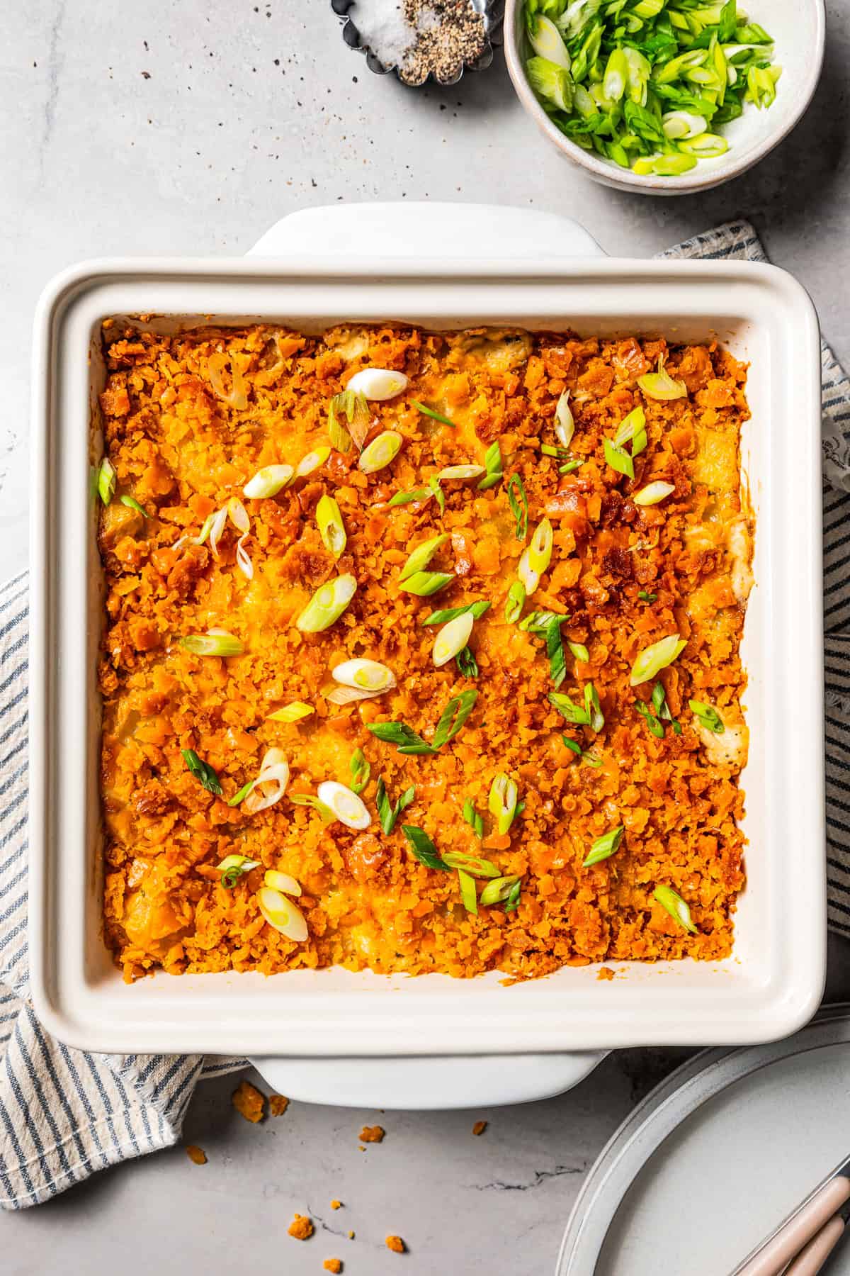 Overhead view of a baking dish with baked cheesy potatoes garnished with sliced green onions.