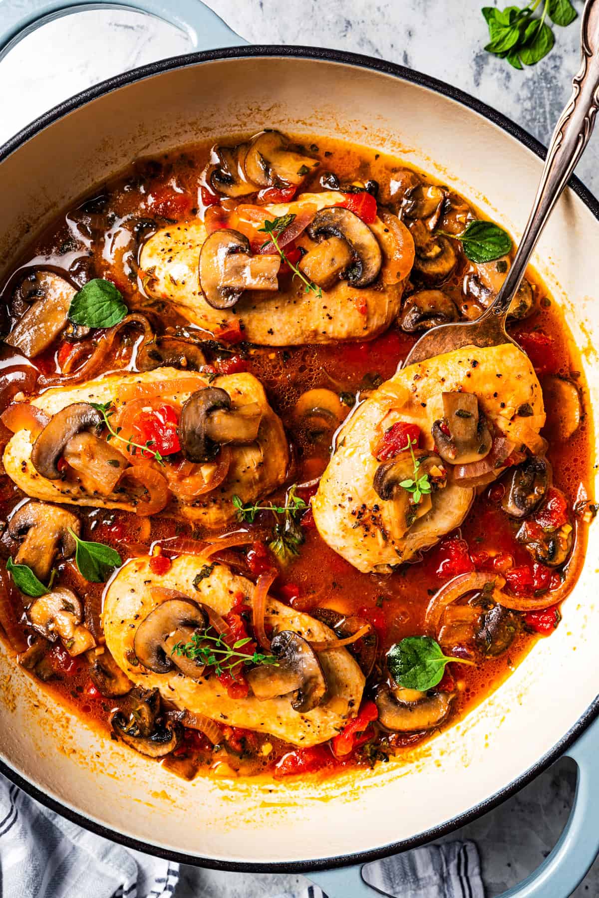 Overhead view of chicken chasseur in a pot and garnished with fresh herbs.