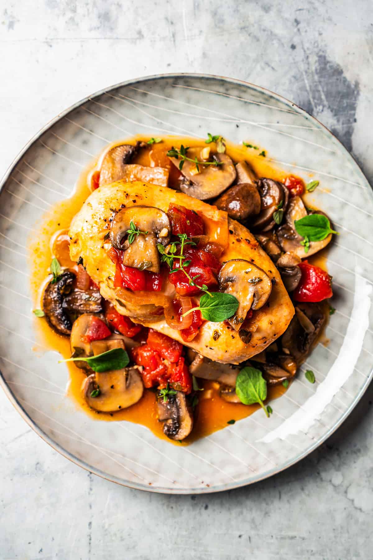 Dinner plate with chicken breast served with a sauce and mushrooms.