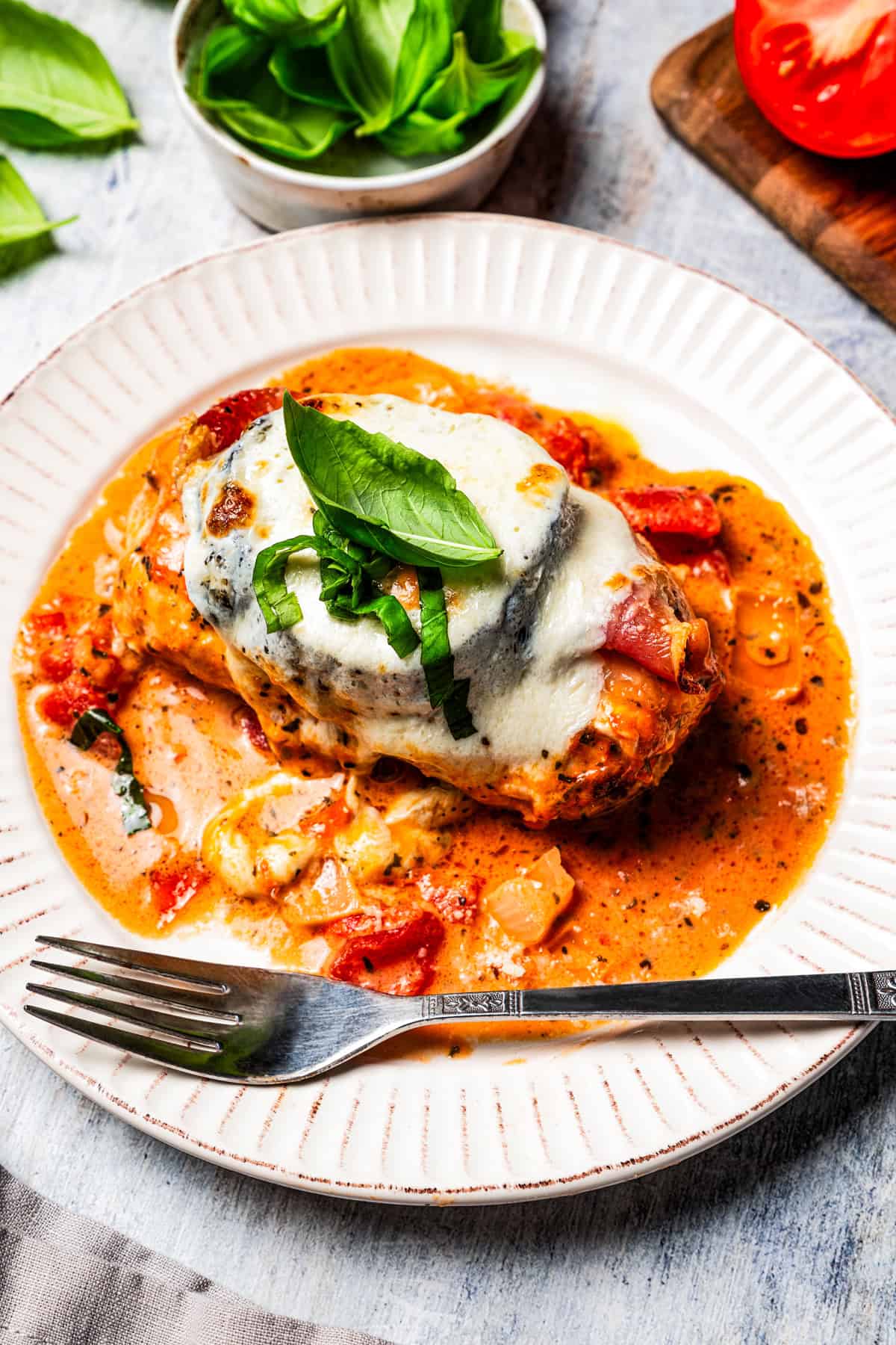 This Chicken Sorrentino is made with juicy chicken breasts layered with prosciutto, roasted eggplant, and three cheeses in a rich marinara sauce. Serving of chicken Sorrentino on a plate.