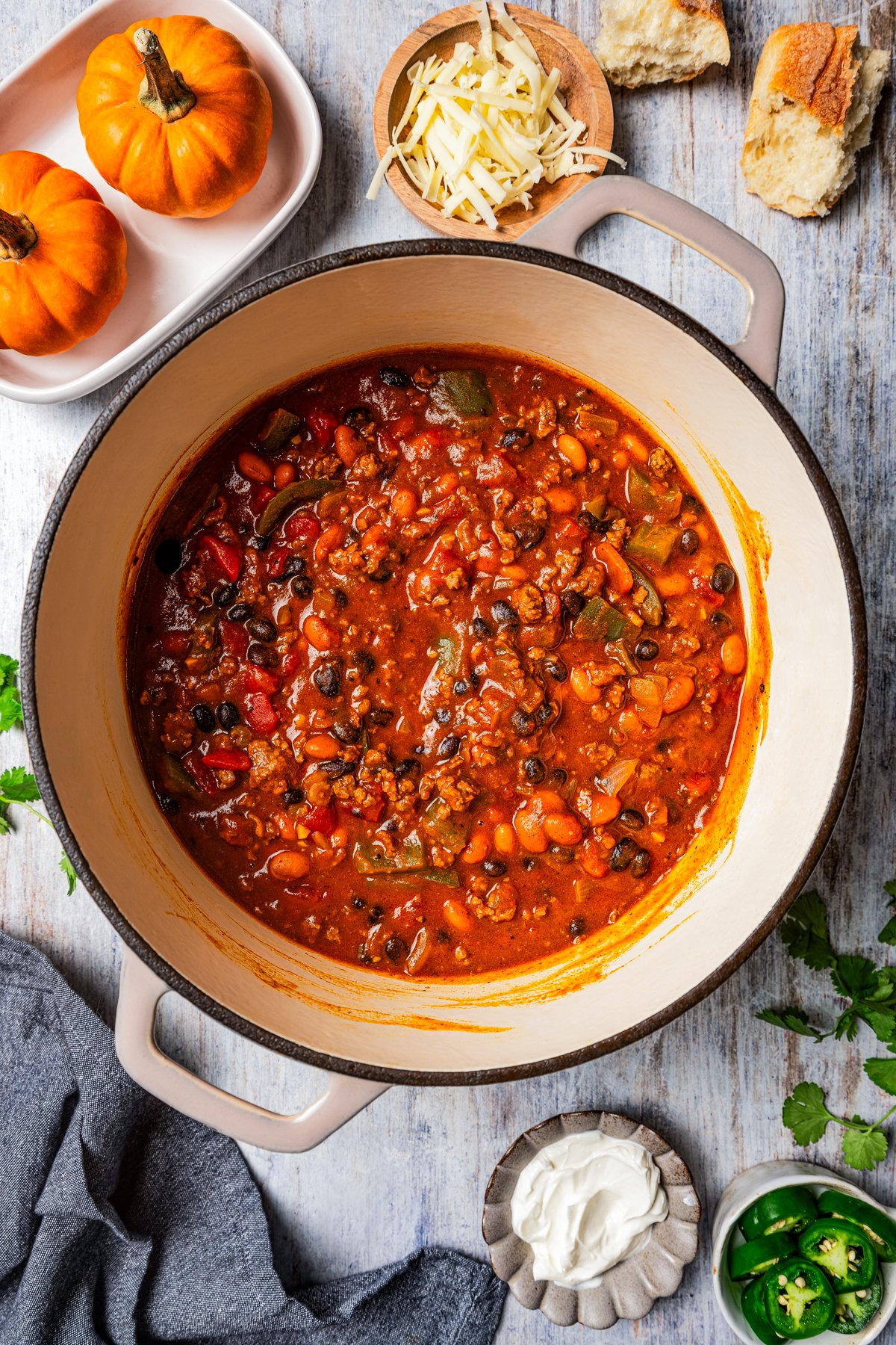 Overhead view of pumpkin chili in a large pot, surrounded by small bowls of toppings.