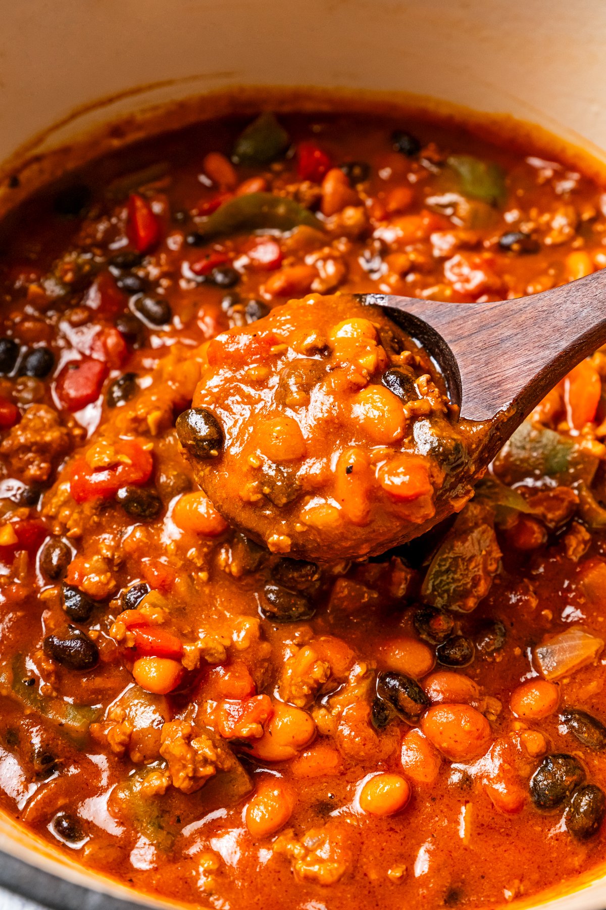 A wooden spoon scooping out pumpkin chili from a pot.