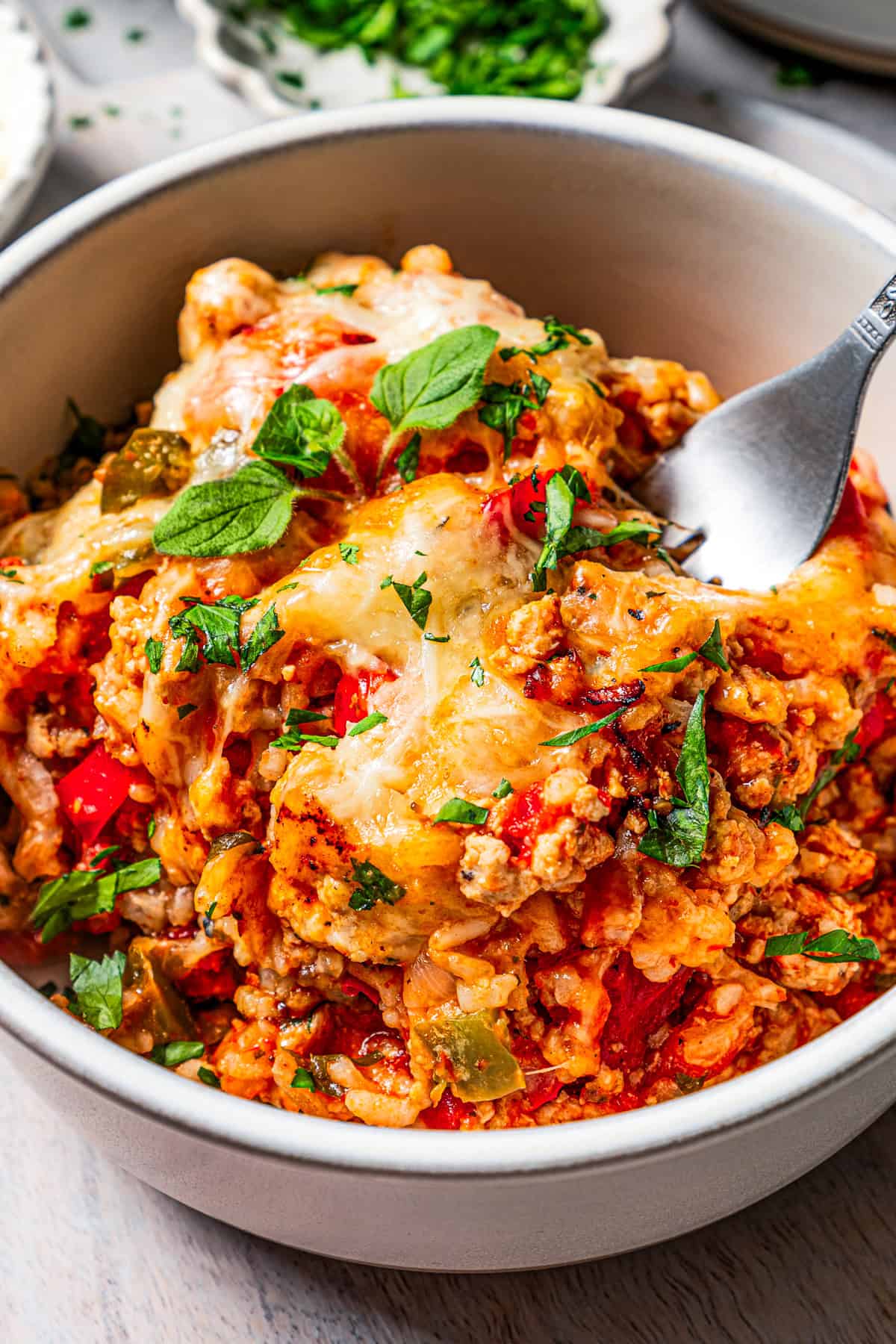 Close-up photo of stuffed pepper casserole served in a bowl, with a fork taking out a bite.