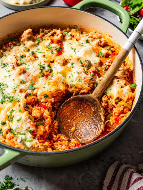 Wooden spoon resting in a baking dish with stuffed pepper casserole.