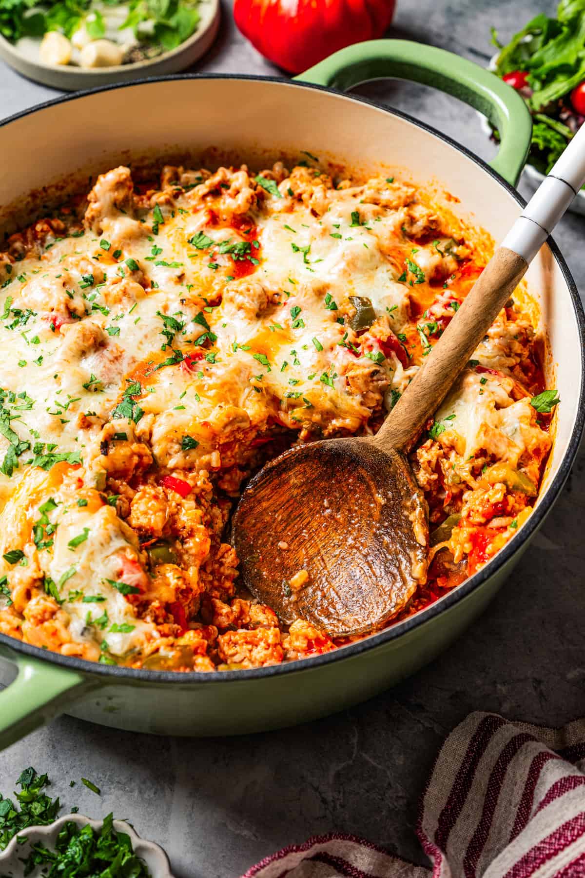 Wooden spoon resting in a baking dish with stuffed pepper casserole.