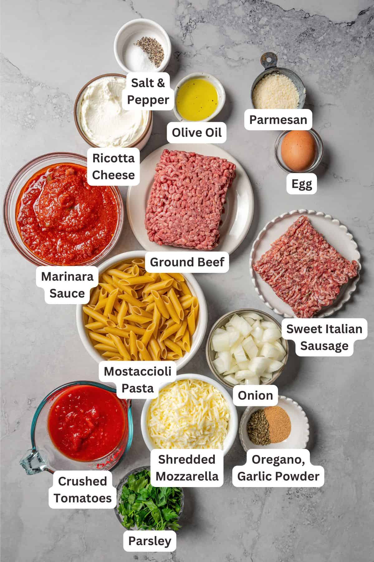 Ingredients for baked mostaccioli with text labels overlaying each ingredient.