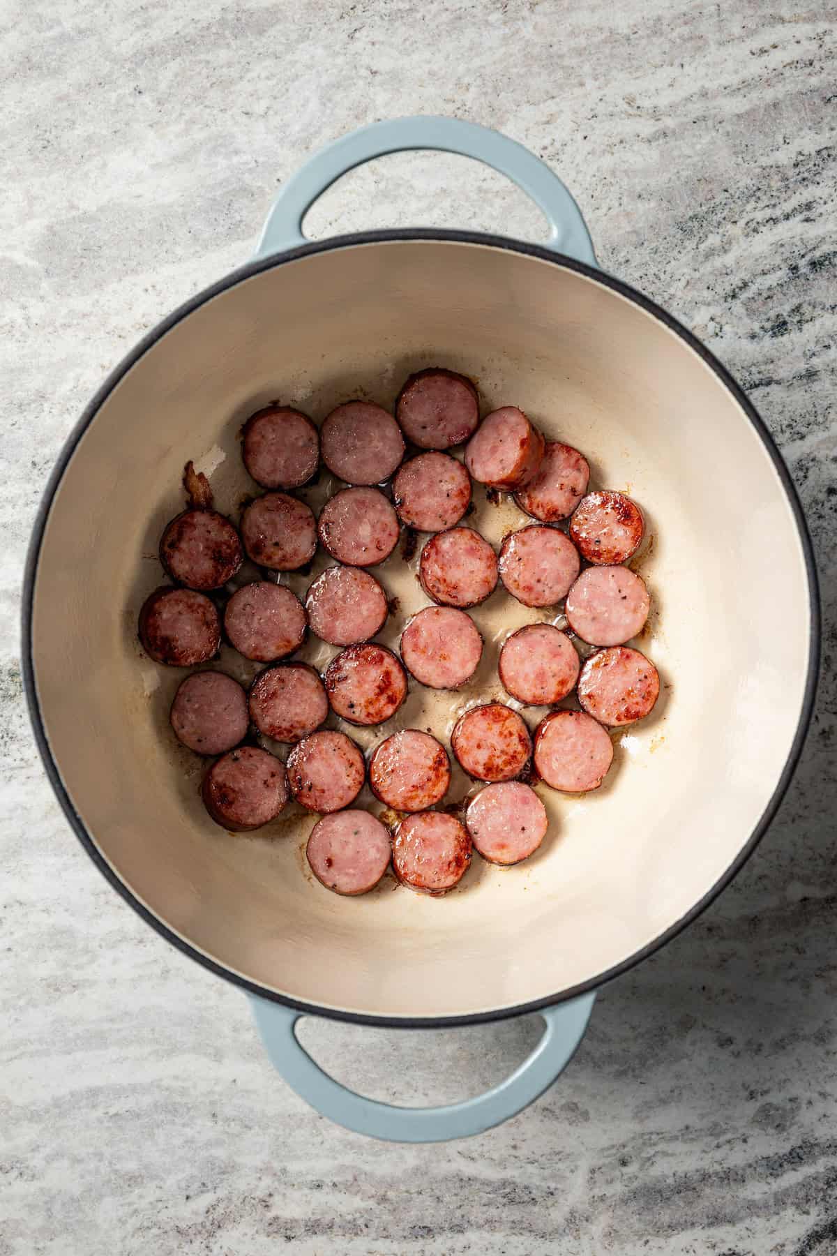 Browned kielbasa slices in a soup pot.