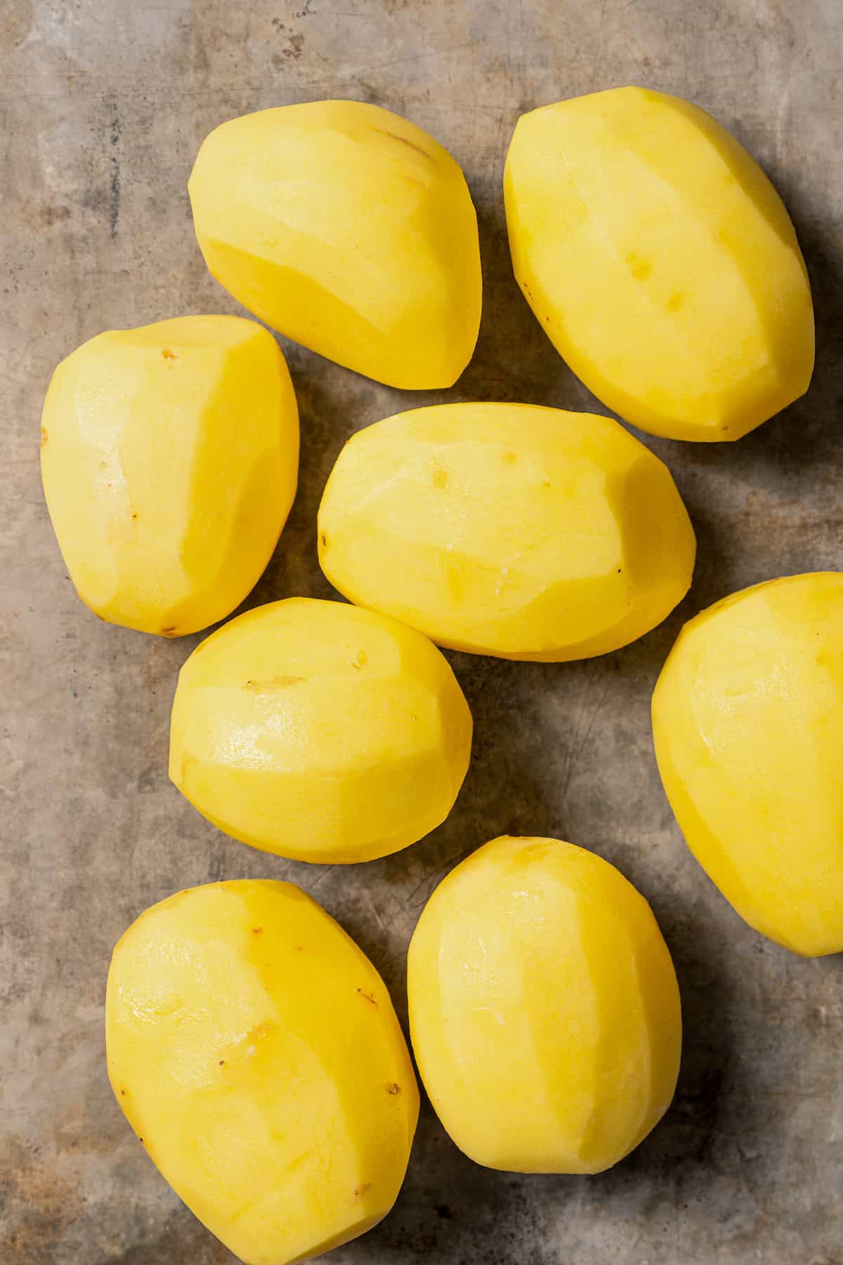 Overhead view of peeled potatoes on a countertop.