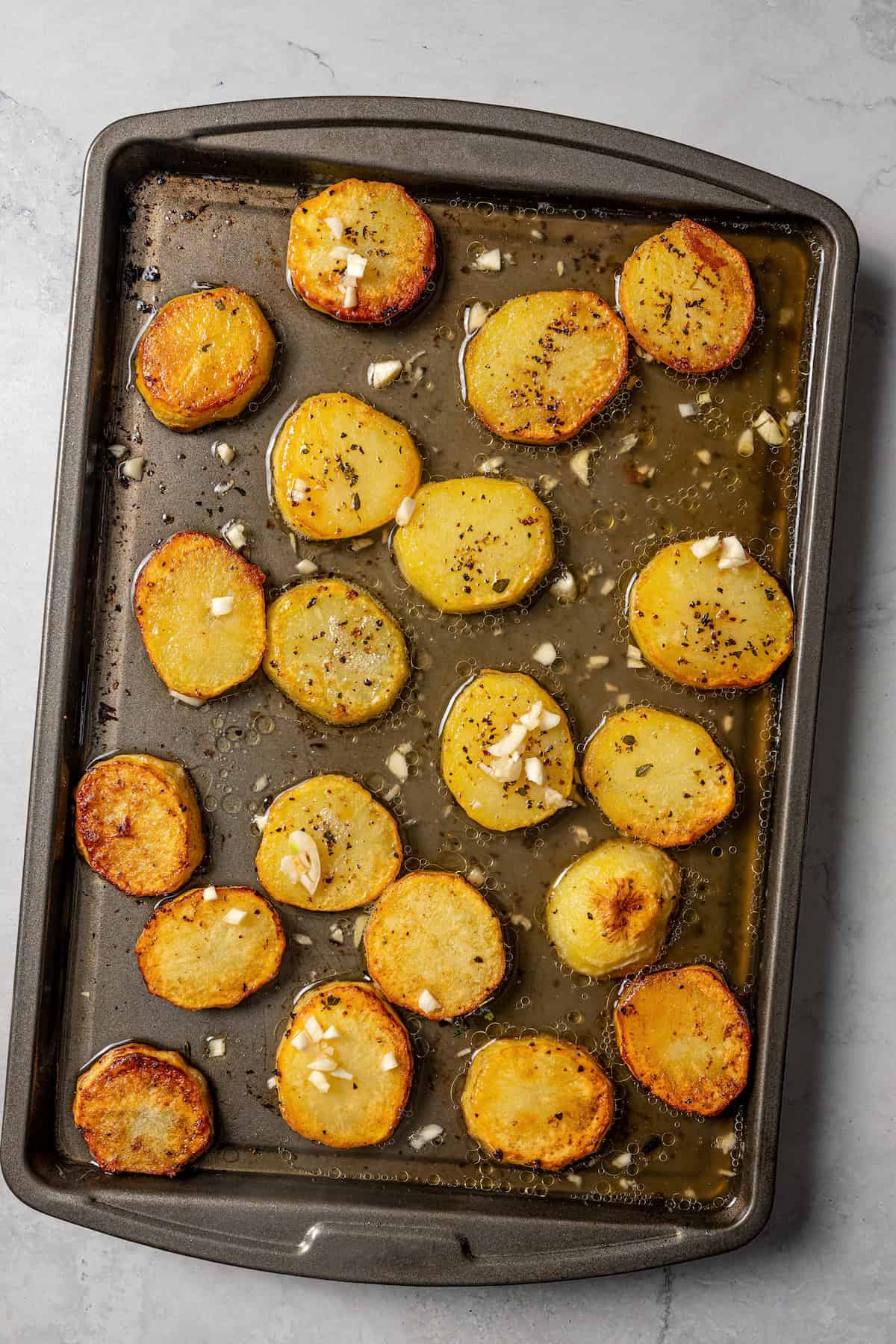 Roasted potato slices on a baking sheet.