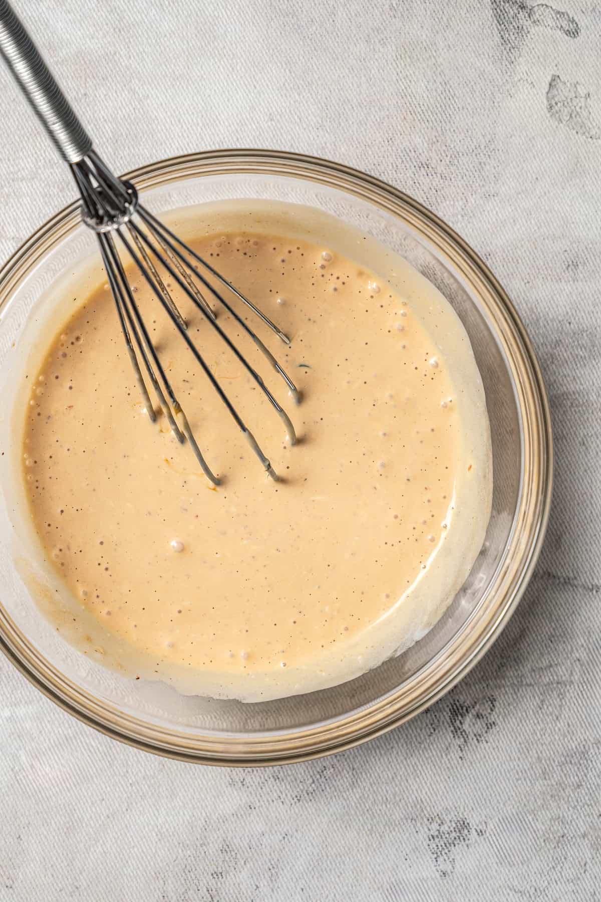 Italian chicken marinade in a glass bowl with a whisk.