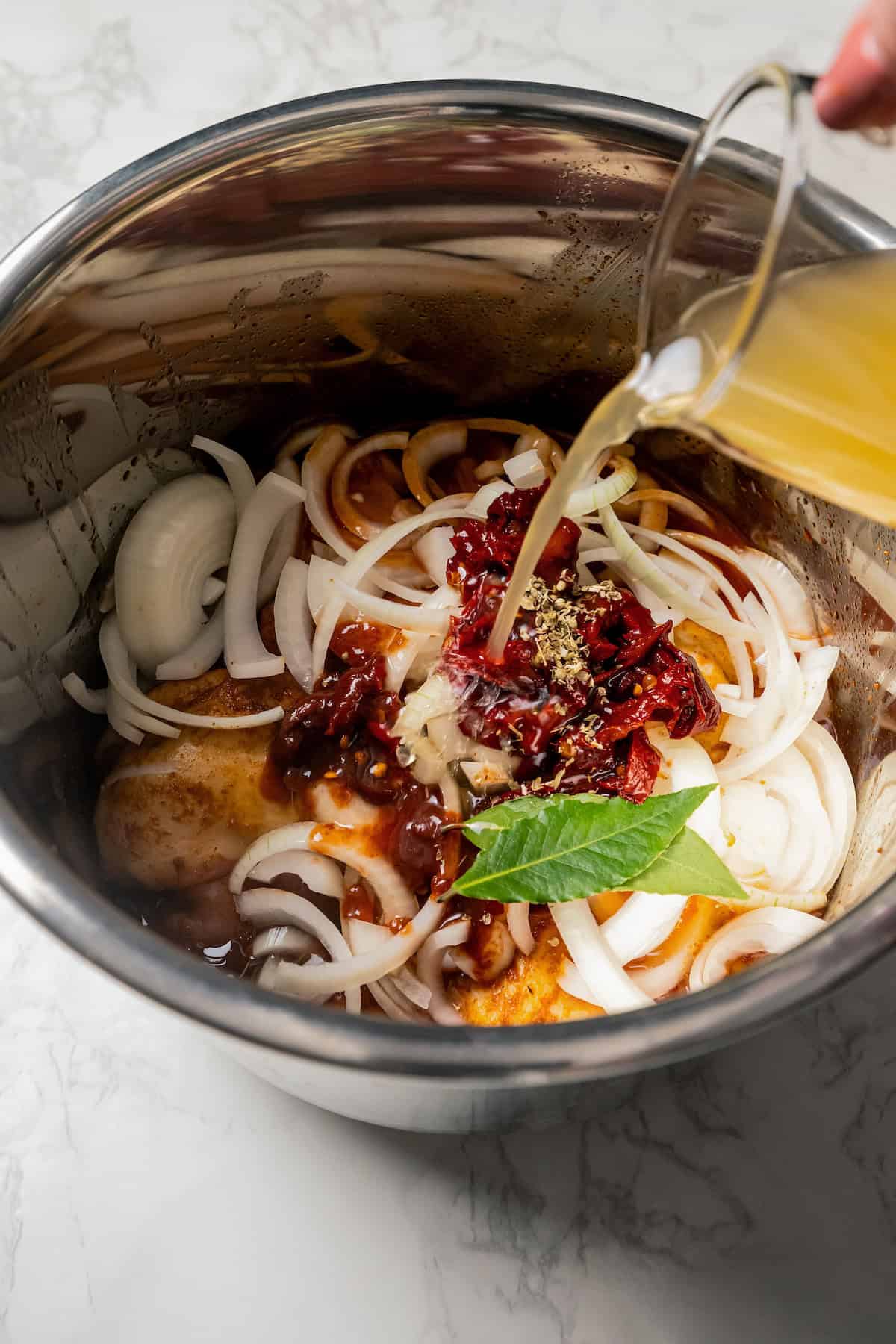 Broth added to a bowl of chicken tinga ingredients.