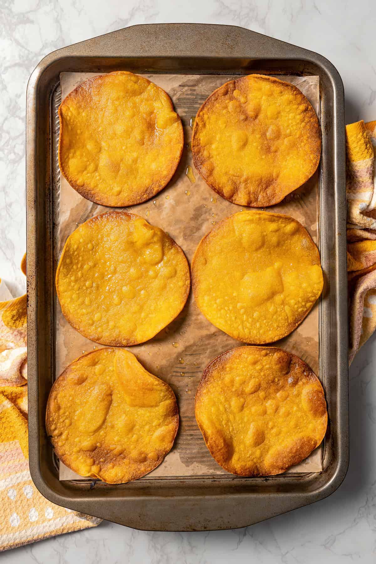 Overhead view of baked tostadas on a lined baking sheet.