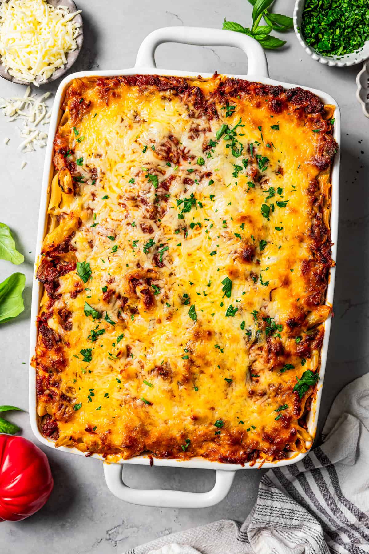 Overhead shot of baked mostaccioli in a large casserole dish, garnished with fresh herbs.