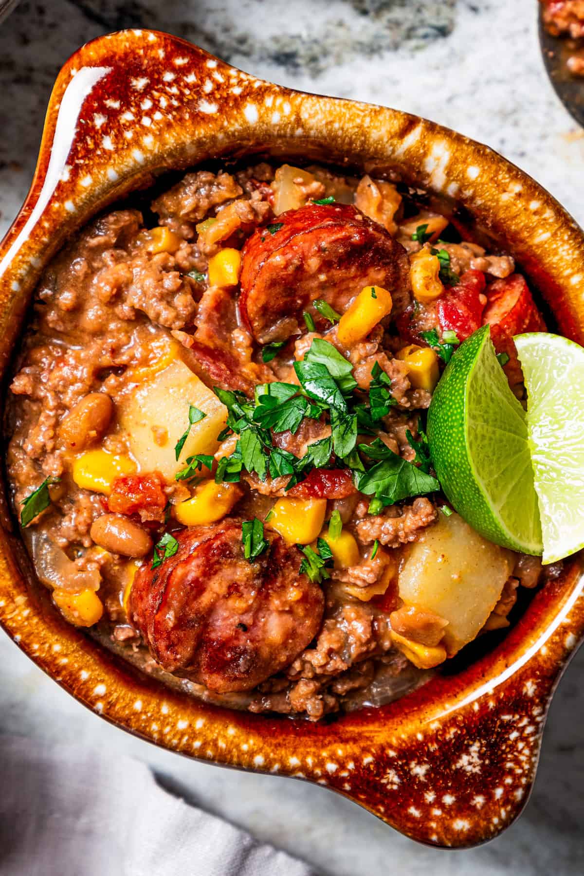 Cowboy stew made with potatoes and ground beef and served in a crockery bowl garnished with cilantro.