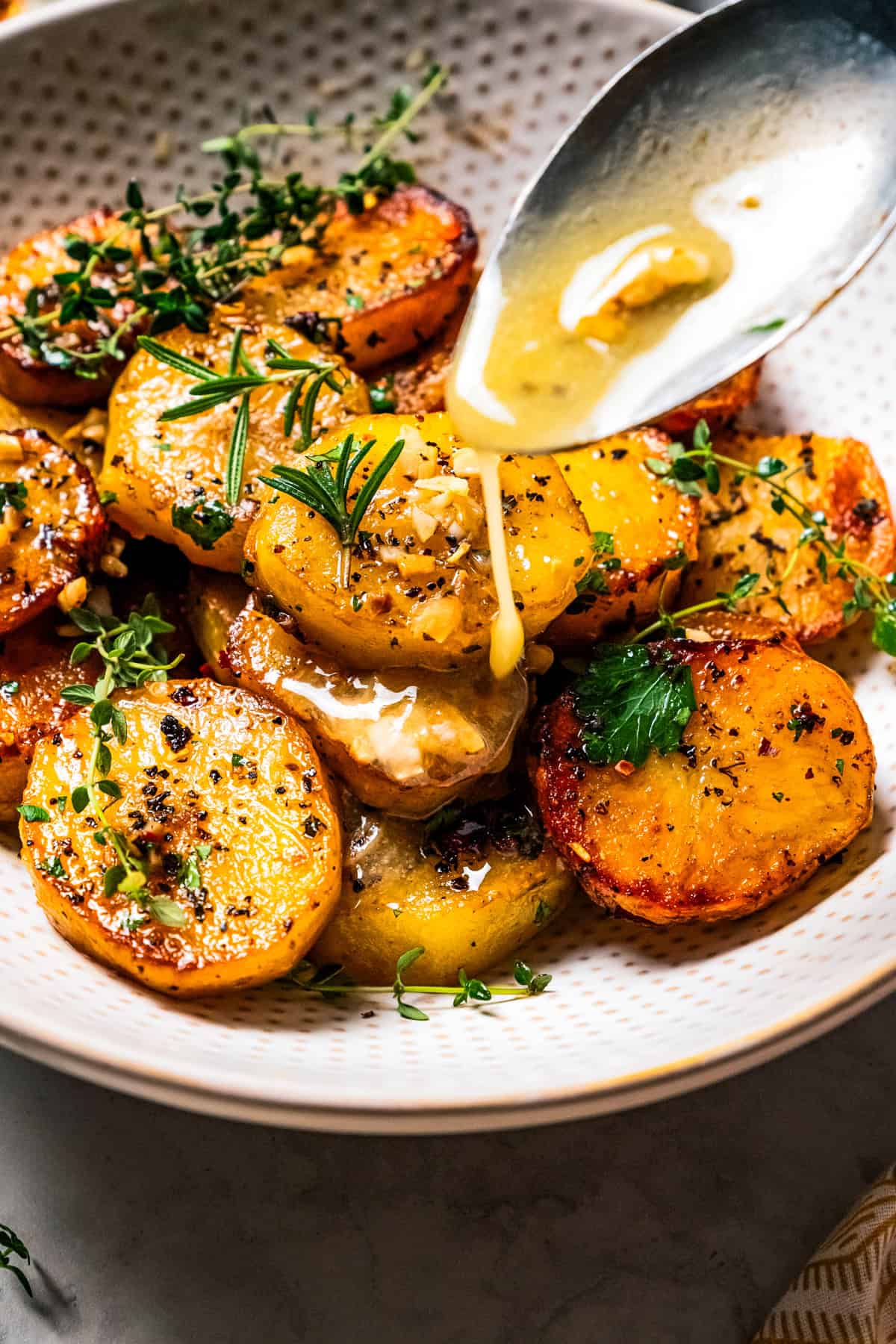 Pouring butter over roasted potatoes.