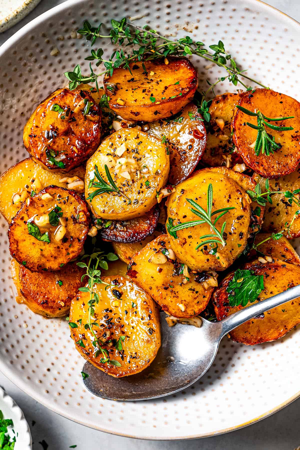 Melting potatoes served in a bowl and garnished with fresh herbs.