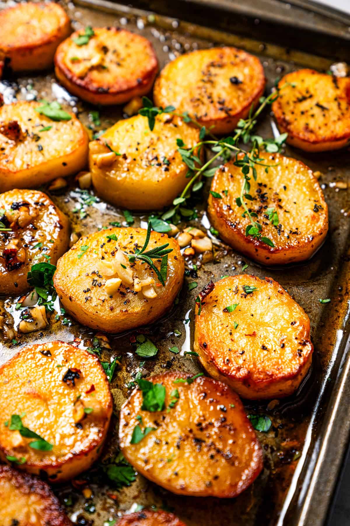 Melting potatoes on a baking sheet garnished with thyme.