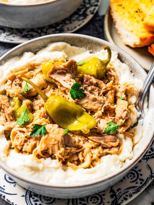 Mississippi chicken served over a bowl of mashed potatoes.