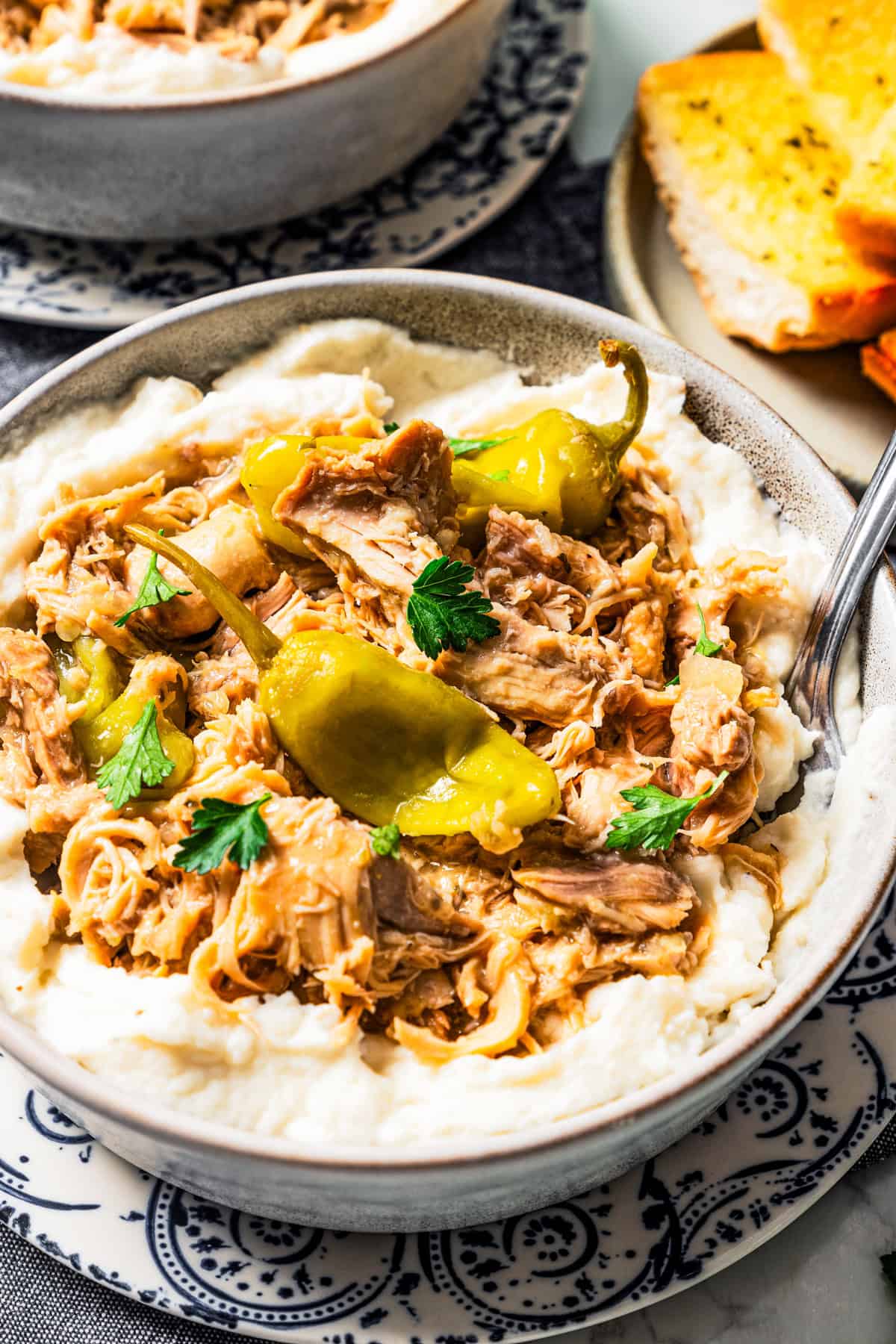 Mississippi chicken served over a bowl of mashed potatoes.