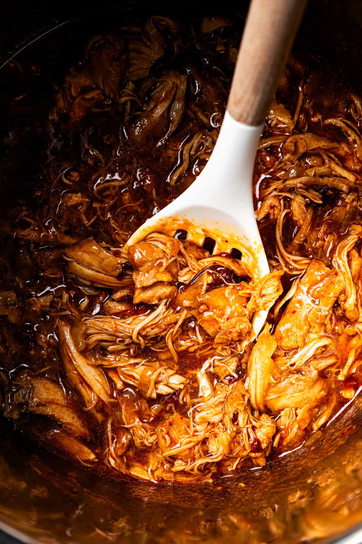 A spoon resting in a pot of chicken tinga.