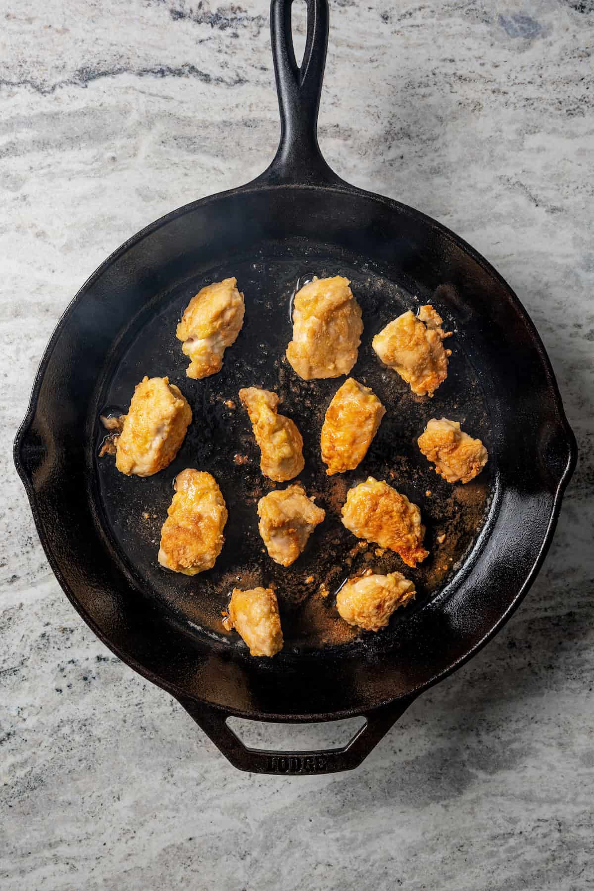 Seared chicken pieces in a cast iron skillet.