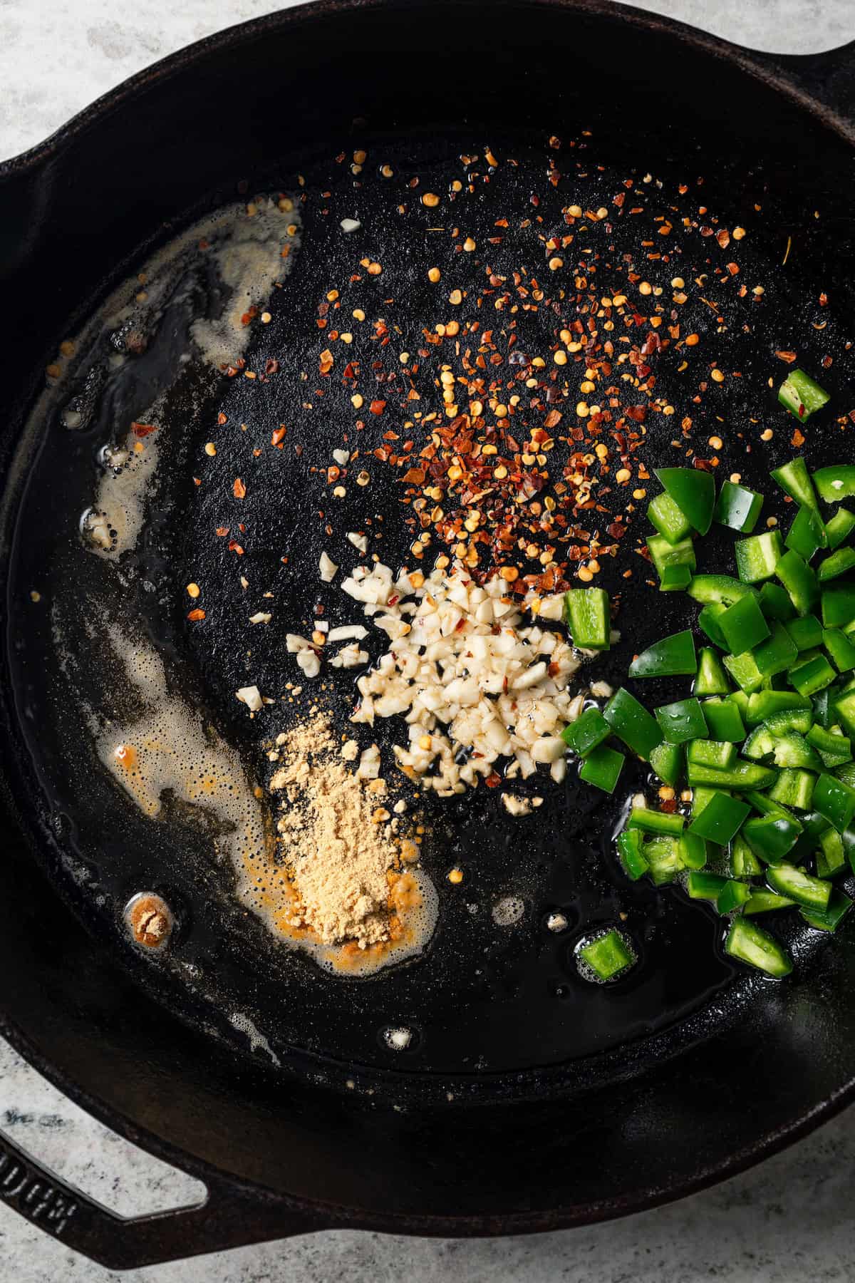 Minced garlic, onions, jalapeño, and seasonings added to a skillet.