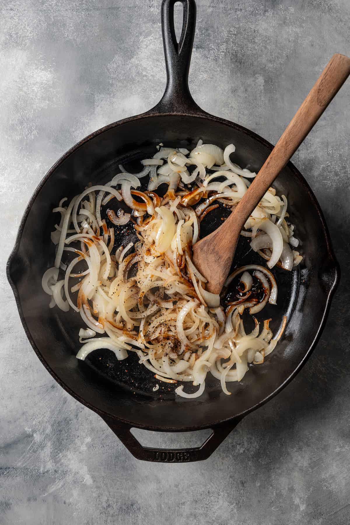 Seasonings added to sautéed onions in a cast iron skillet.