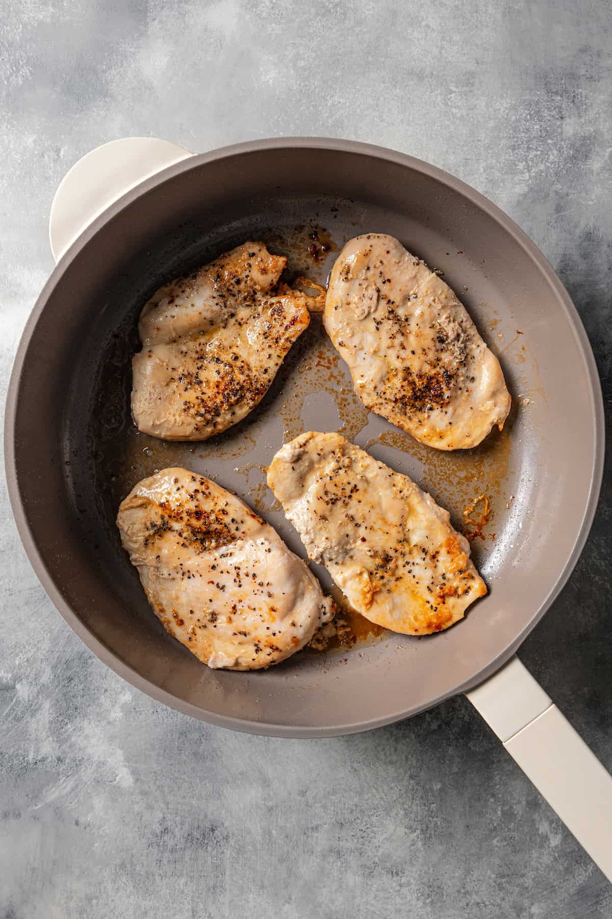 Seared chicken breasts in a skillet.