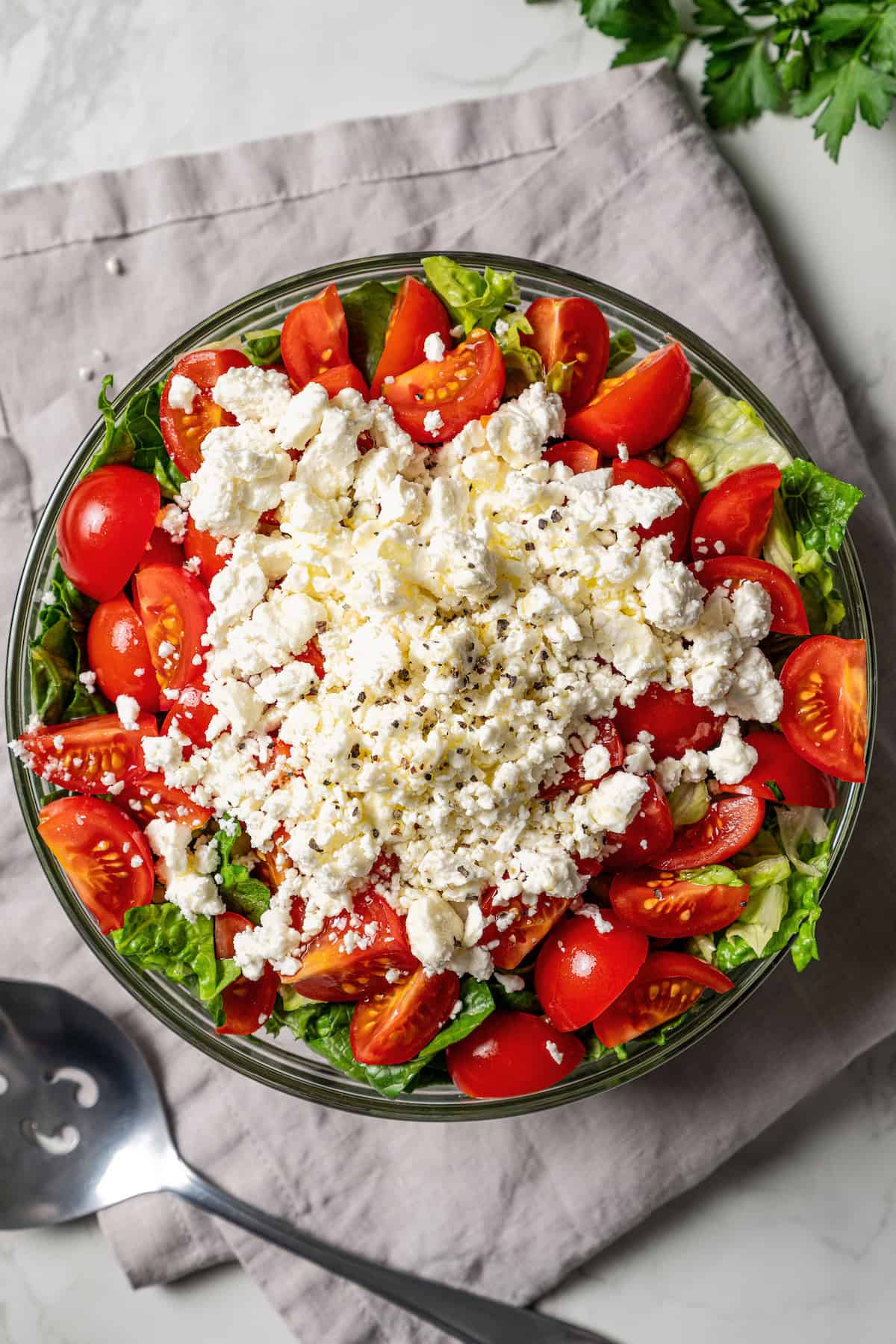 Mediterranean seven layer dip topped with crumbled feta in a glass bowl.