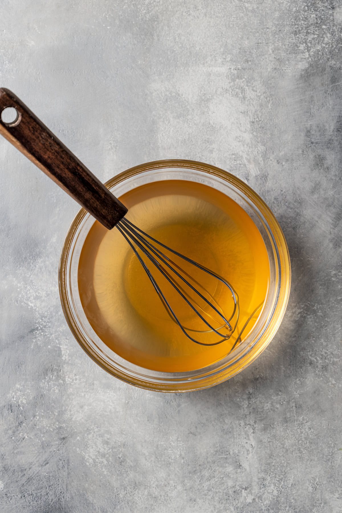 Vinegar dressing in a bowl with a whisk.