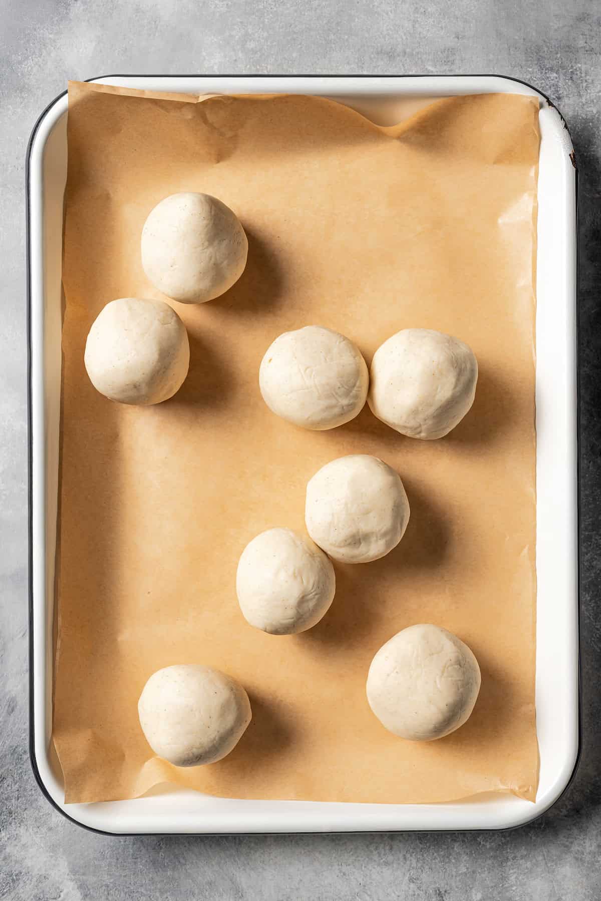 Round pupusa dough balls on a parchment-lined tray.