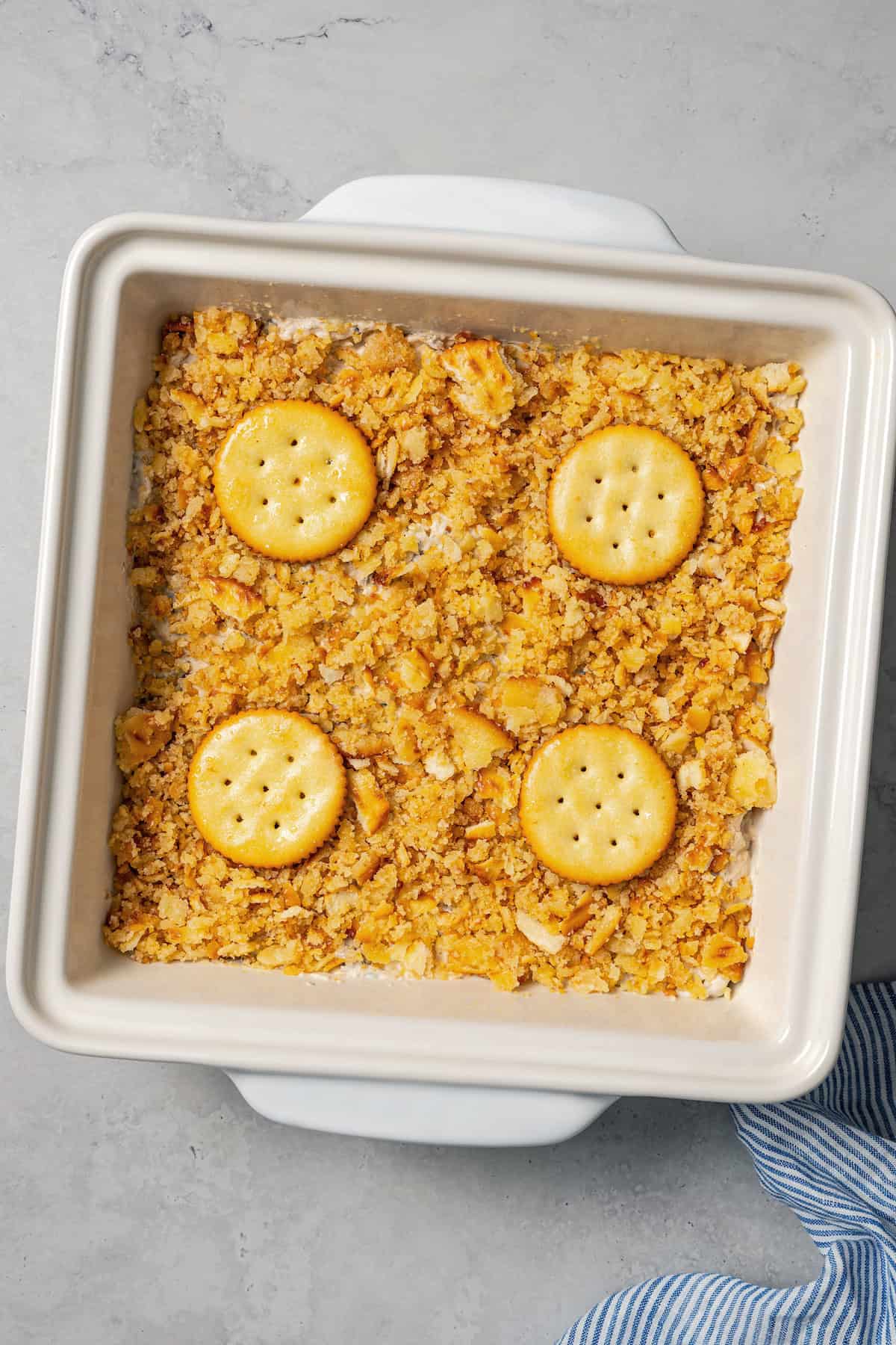 Overhead view of an unbaked Ritz chicken casserole topped with Ritz crackers in a baking dish.