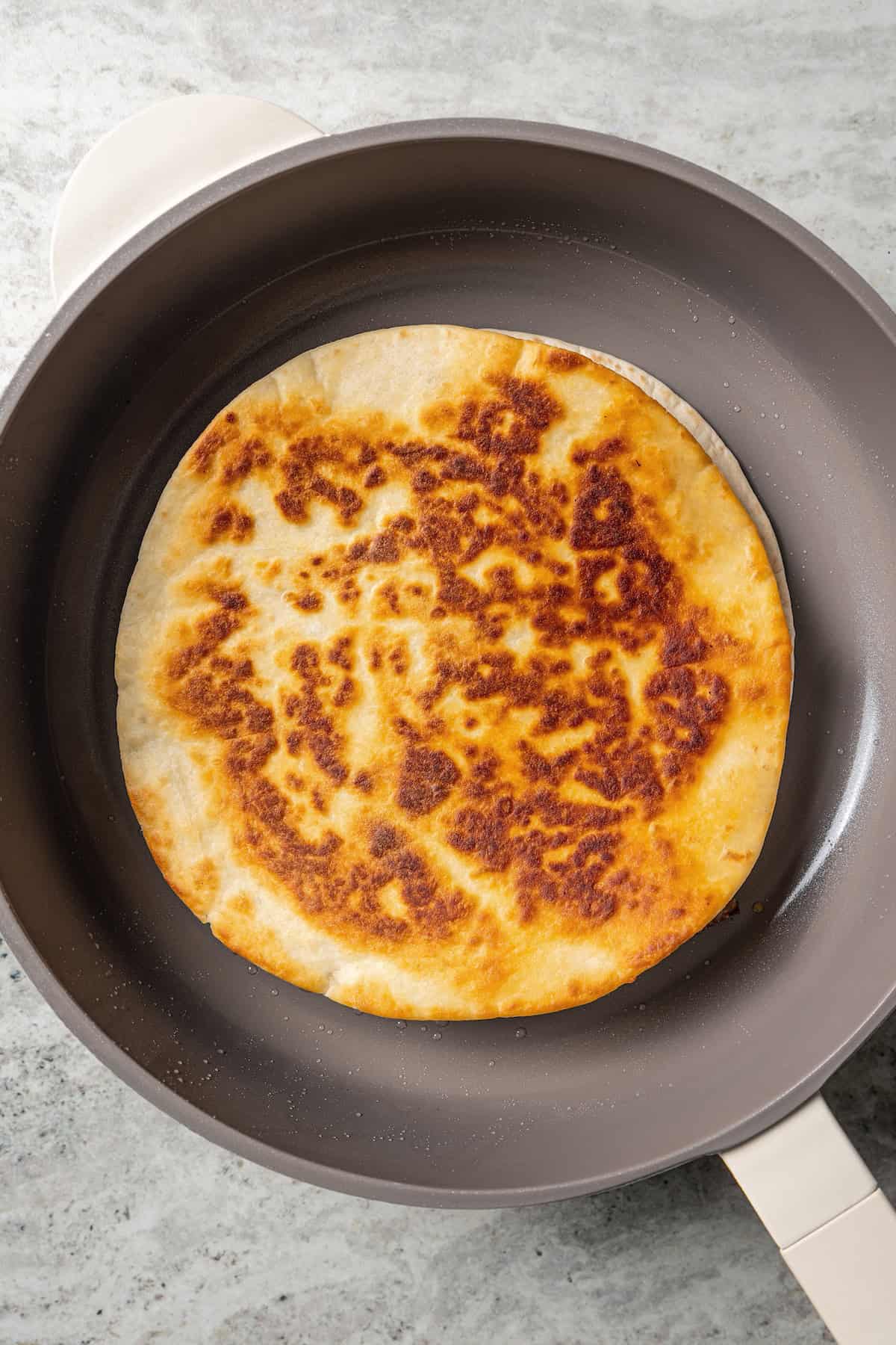 Overhead view of a cooked steak quesadilla in a skillet.