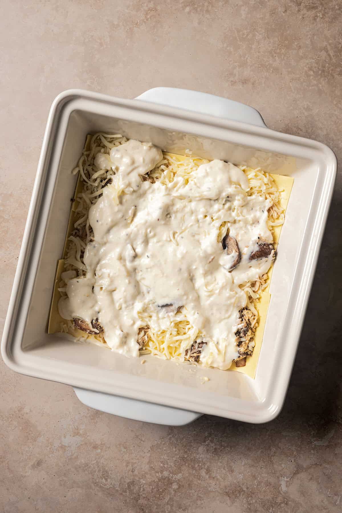 Partially assembled white chicken lasagna in a baking dish.