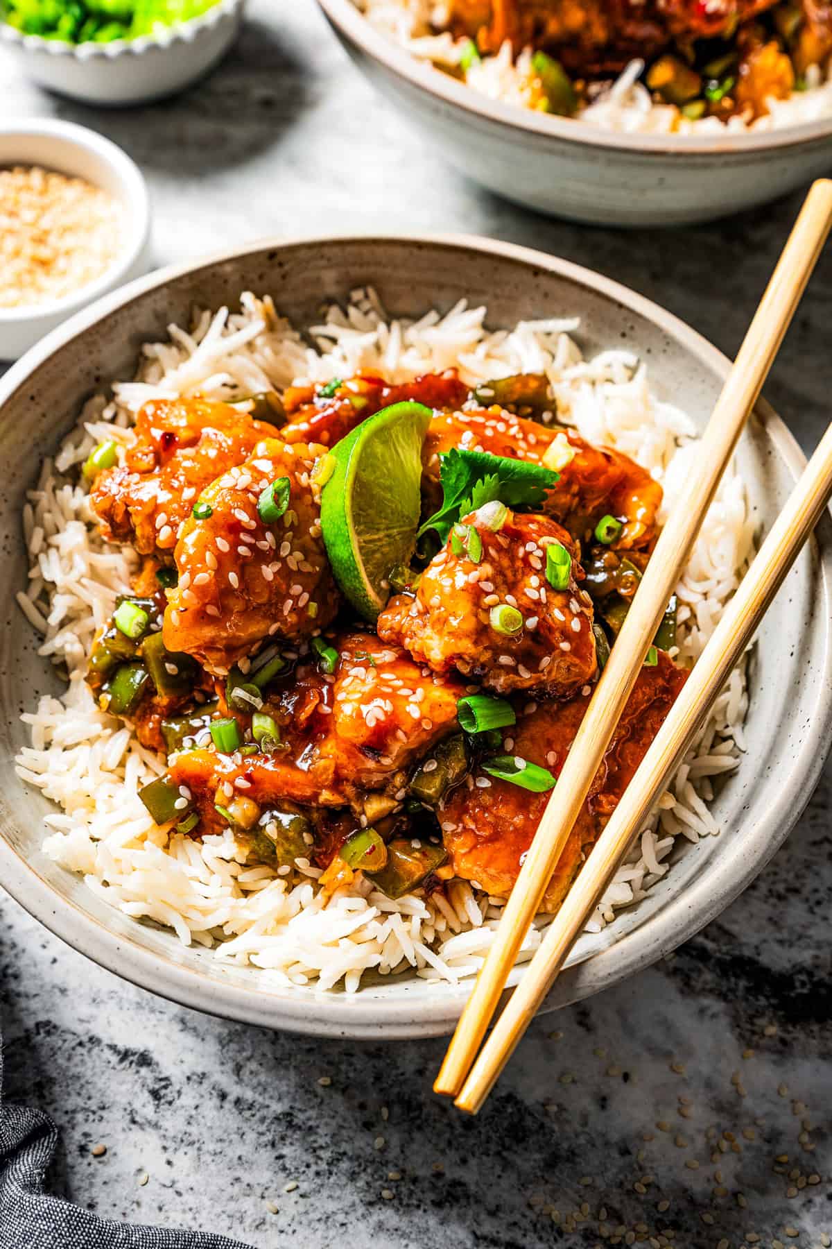 Empress chicken served over white rice with a pair of chopsticks resting on the edge of the bowl, and a second bowl of chicken and rice in the background.