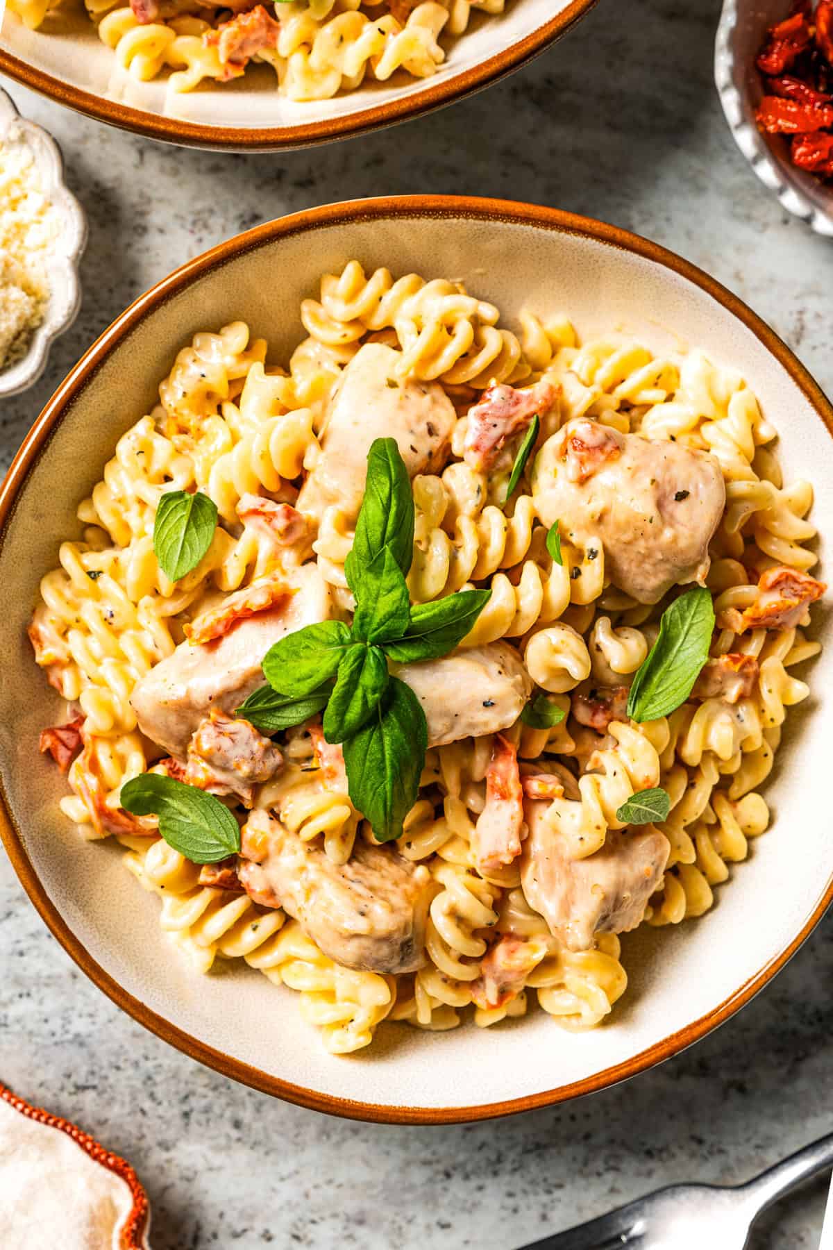 Pasta with chicken served in a bowl and garnished with fresh basil leaves.