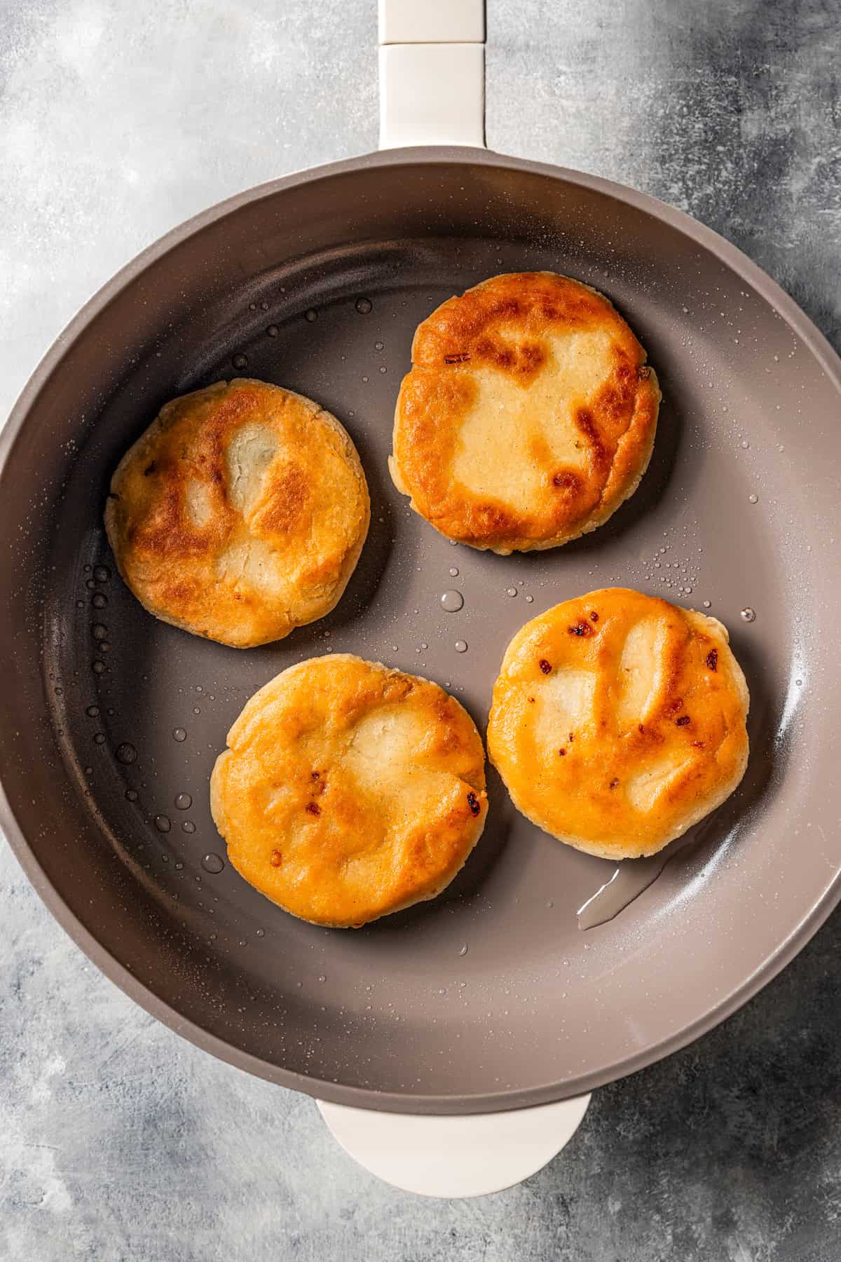 Frying pupusas in a skillet.