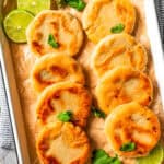 Pupusas arranged in rows on a tray garnished with lime slices.