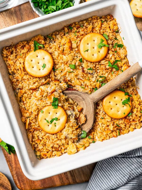 Overhead view of a Ritz chicken casserole topped with Ritz crackers in a baking dish with a wooden spoon scooping out the food.