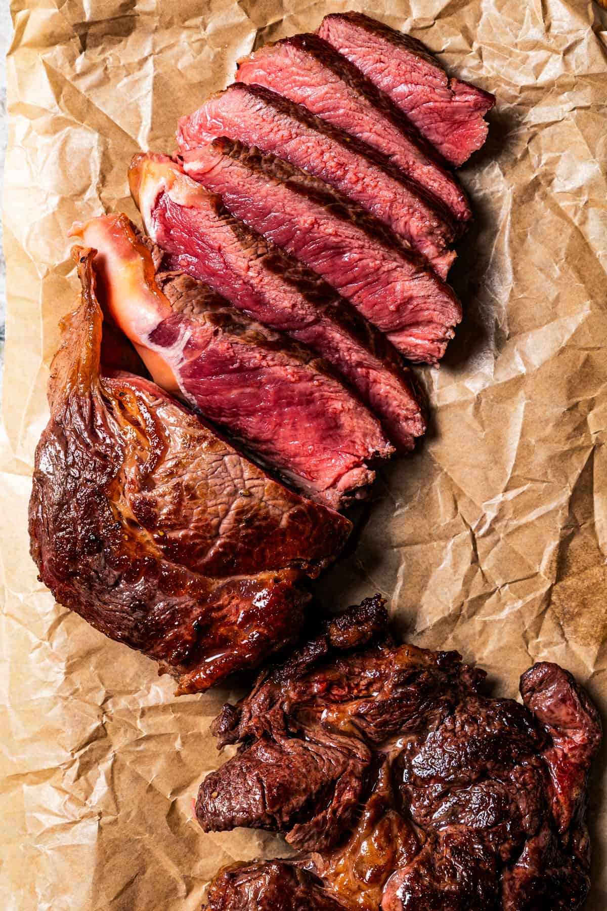 Seared steak cut into slices on a piece of parchment paper.