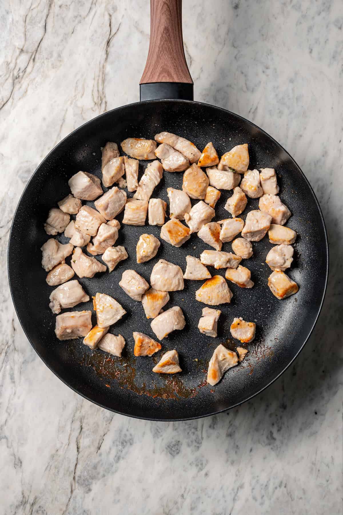 Browned chicken pieces in a skillet.