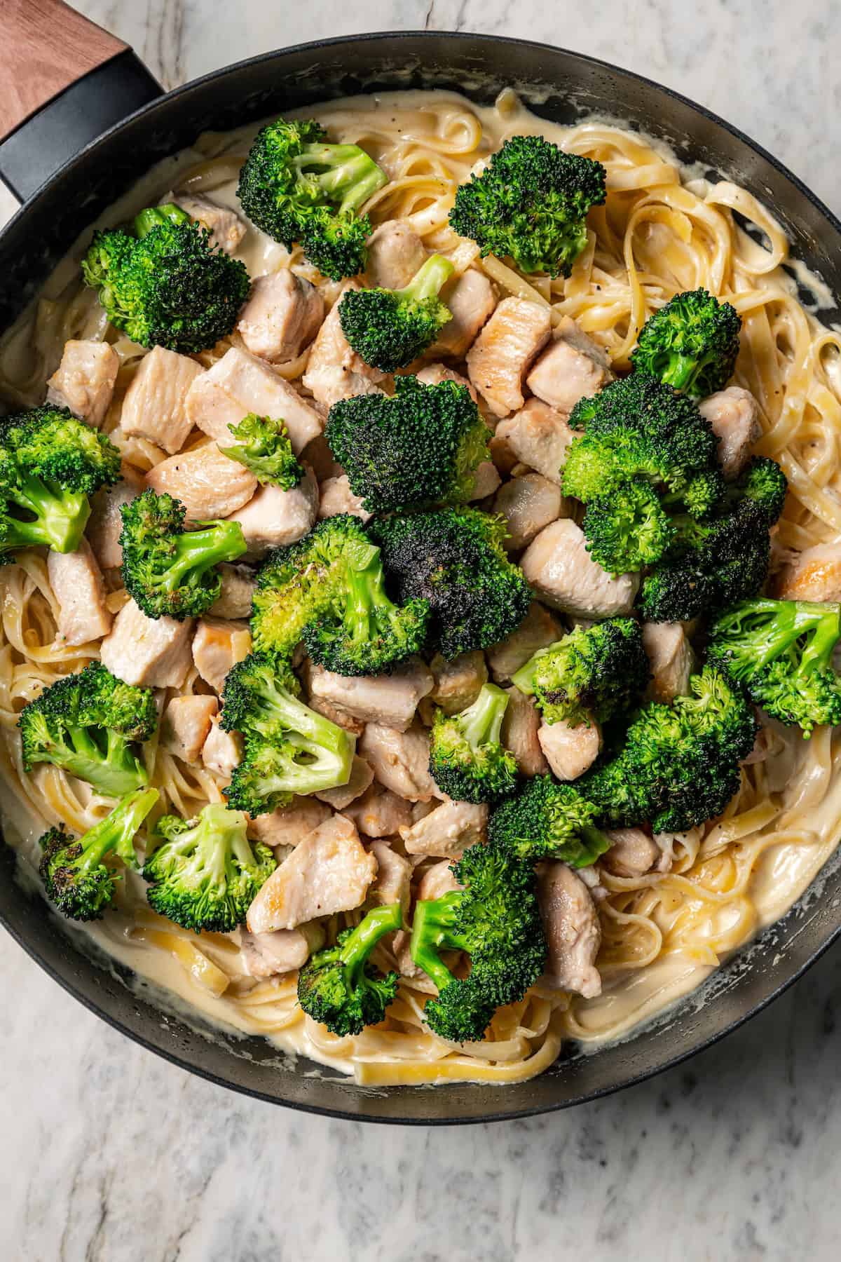 Broccoli florets and chicken pieces added back into the pan with fettuccine alfredo.