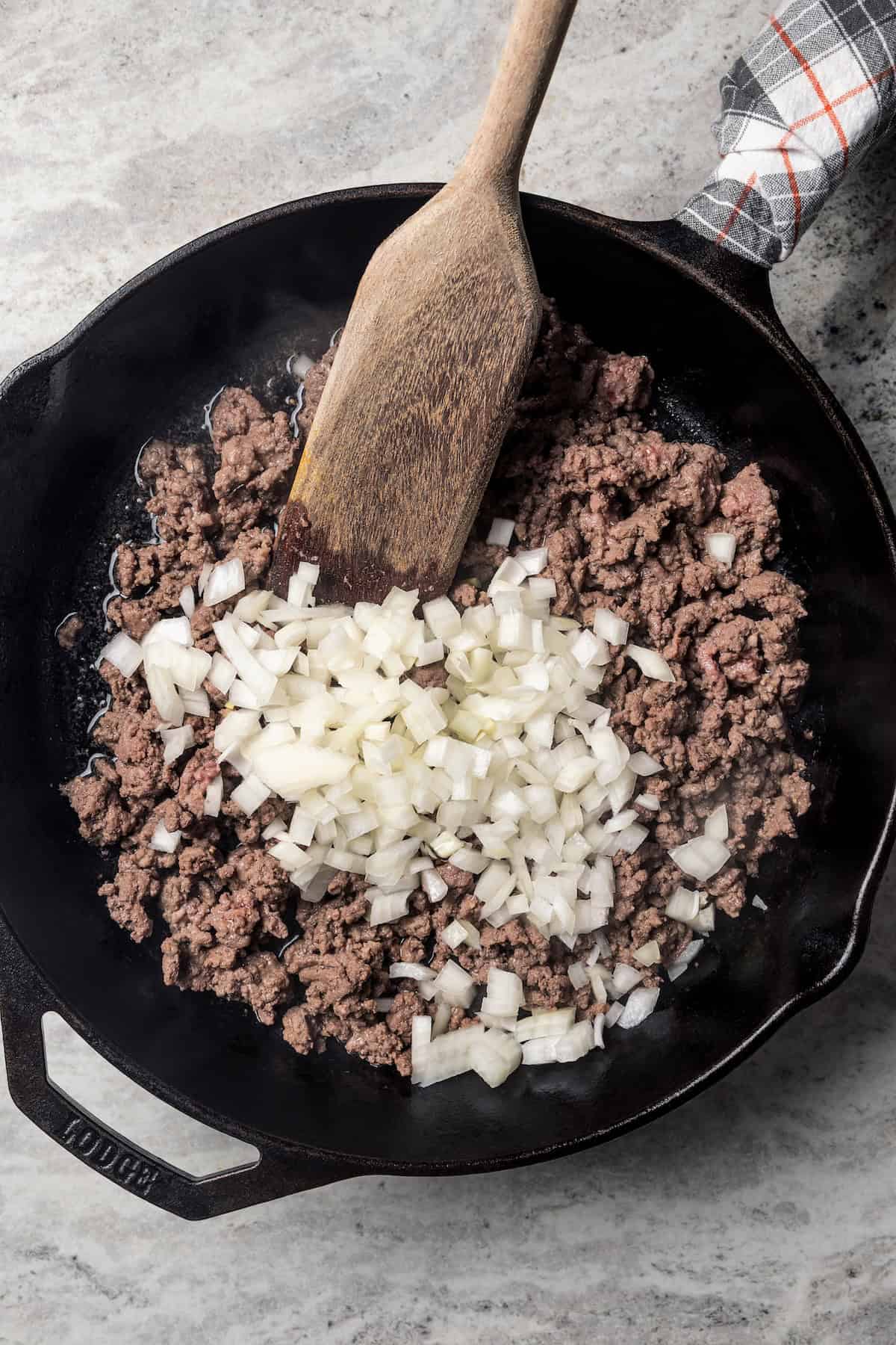 Ground beef and onions browning in a skillet.