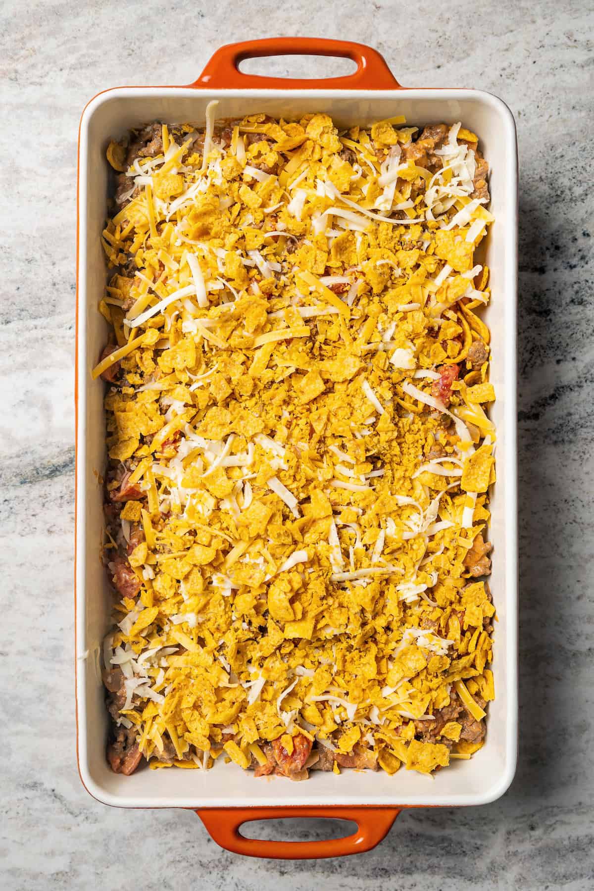 Taco casserole topped with shredded cheese in a baking dish.