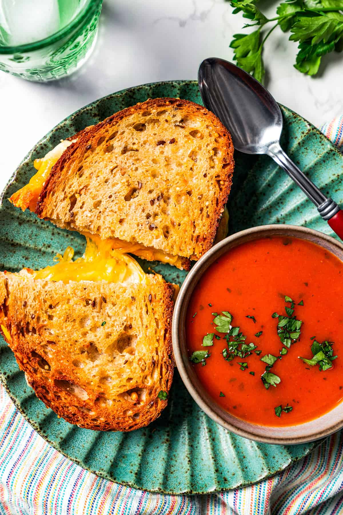 Grilled cheese sandwich served on a plate with a bowl of tomato soup.