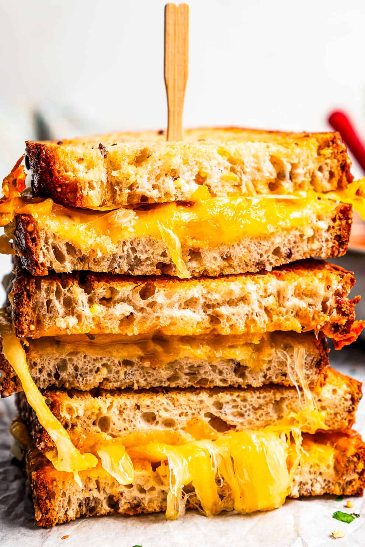 Air Fryer Grilled Cheese Sandwich halves stacked on a sheet of parchment paper and held together with a skewer.