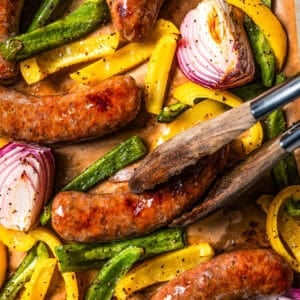 Tongs turning over Italian sausage in casings.