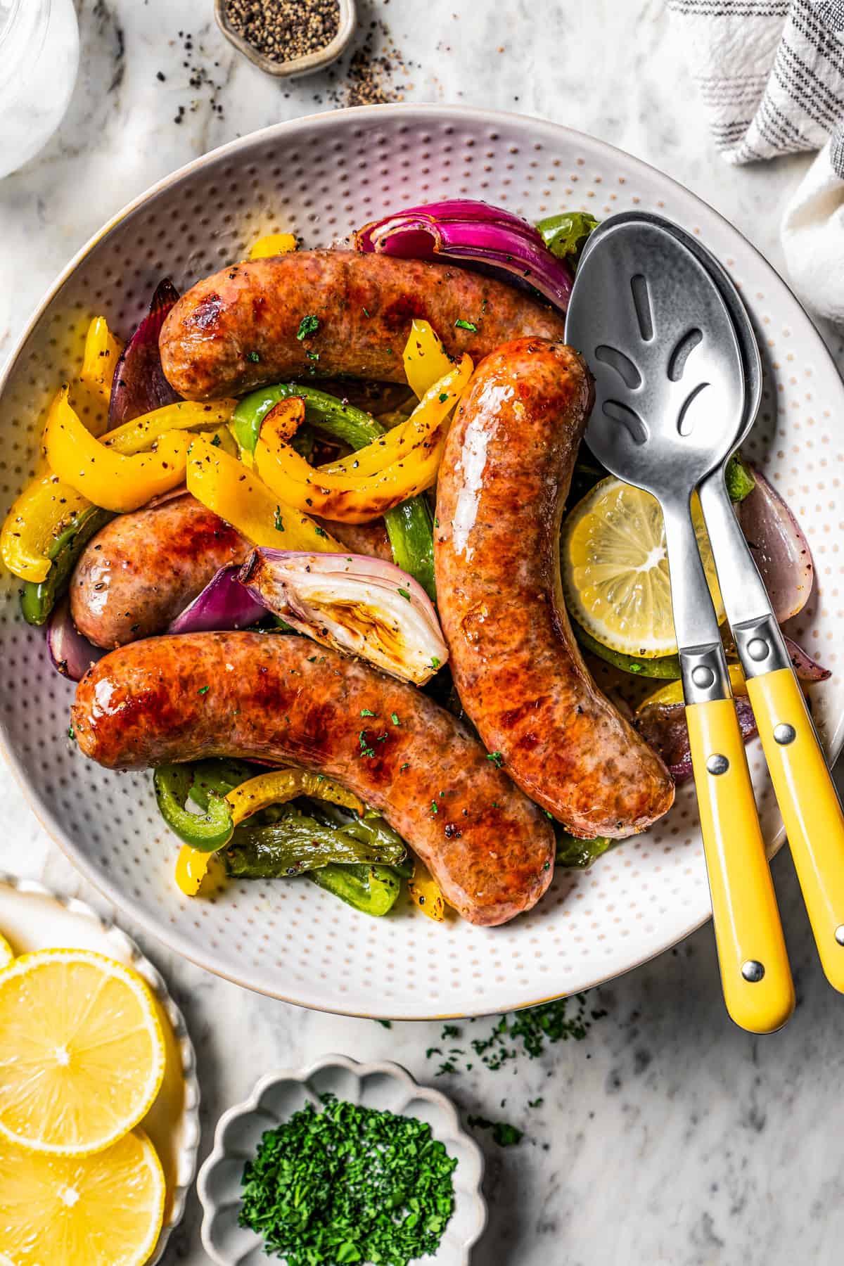 Italian sausage and peppers served in a bowl with two serving spoons.