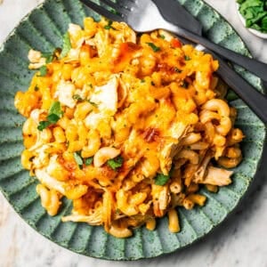 Serving of buffalo mac and cheese on a green stoneware plate next to a fork and knife.